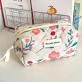 Detailansicht der gesteppten Kosmetiktasche mit Blumenmuster und Etikett auf weißem Tisch - Achteckige Tasche (Klein Mini)