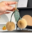 Detail of khaki faux fur cherry pendant with green leather leaves and golden clasp - Khaki