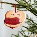 Wooden heart hug pendant with red and natural wood tones hanging on a Christmas tree - Heart Hug Style 3