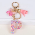Close-up of letter P resin keychain with colorful star sequins, pink butterfly and tassel - Letter P