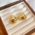 Nahaufnahme von vergoldeten Zirkon-Ohrringen mit braunen Tigeraugen-Perlen in einer Box - Goldbraun