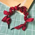 Close-up of a twisted red fabric headband with a soft glossy finish on plaid background - Red (Cloth Pleated Knot)