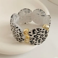 Detalle macro de cuentas de acrílico de leopardo y espaciadores dorados en un brazalete - Blanco