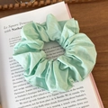 Close-up of light green fabric scrunchie on vintage book pages with soft textures - Lake Green