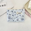 Detailed macro shot of quilted floral cosmetic pouch with blue mermaid cat illustration - Jellyfish