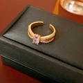 Dettaglio anello dorato con zircone viola ovale e design a coste su scatola per gioielli - Oro Con Pietre Preziose Viola (WR496)