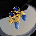 Orecchini vintage dorati con cristalli blu e fiocco su sfondo di uno specchio - Stile pietra blu con fiocco lungo