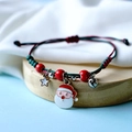 Close-up of adjustable braided red Christmas bracelet with Santa and bell charms - Hat Santa