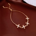 Close-up of golden adjustable bracelet with four zircon cross flower charms on silk - Gold