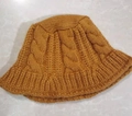 Detail of ginger yellow knitted bucket hat featuring a classic thick cable stitch pattern - M (56-58cm) / Yellow