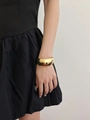 Polished gold double-layer cuff bracelet worn by a model in a black dress detail - Type G Gold