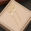 Detailed macro view of gold-plated drop earrings with clear square crystals on velvet pad - White Tassel Earrings
