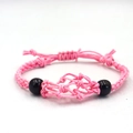 Close-up of pink woven mesh bracelet with black spherical beads and handmade textures - Bracelet / Pink