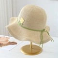 Detail of straw hat featuring yellow tulip embroidery and a green ribbon bow accent - Beige with Green Ribbon