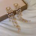 Detailed view of long gold tassel earrings with pearls on silk background - Pearl Tassel Ear Buckle