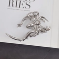 Detailed view of a silver spider claw clip on a minimalist white book background - Large Spider Hair Claw / Silver