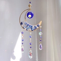 Blue Evil Eye moon suncatcher with crystal prisms and gold frame hanging in sunlight - Blue
