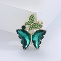 Dettaglio della spilla a farfalla dorata con grandi cristalli smeraldo e strass verdi fitti - Verde