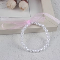 Detail of children's faux pearl bracelet featuring a soft pink organza ribbon bow - 6MM Pure White Pearl With Pink Ribbon Bracelet