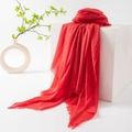 Vibrant red cotton linen scarf with natural frayed edges displayed on a white stand - Coral