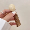 Amber spiral telephone wire hair tie with a beige pearl bead for ponytail styling - Light Yellow
