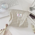 Platliggende weergave van geruite canvas make-uptas met patch en reisaccessoires - Wit