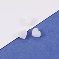 Vue macro de trois breloques en forme de cœur en résine translucide avec paillettes opalines - 8mm / Blanc