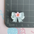 Detalle de lazo de resina de 2cm con flor de cerezo sobre una alfombra de corte graduada - Lazo Sakura Transparente / Azul