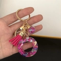 Detailed view of pink resin ball keychain with colorful sequins and golden ring - Small Ball Tassel Clasp / Letter O