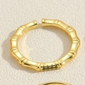Gros plan sur une bague ajustable style bambou doré avec trois zircons verts sertis - Bague Bambou Vert Émeraude