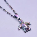 Macro shot of minimalist stainless steel sea turtle pendant with vibrant rainbow finish - Rainbow Color Necklace