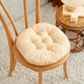 Plump cream-colored round tufted chair cushion on a wooden chair in cozy room setting - [Round] Light Camel