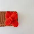 Soft bright orange knit baby scarf in a bow shape with ribbed texture for winter warmth - Solid Color-Orange