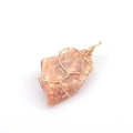 Detail of orange natural stone pendant with handcrafted gold wire wrapping on white background - Strawberry Quartz