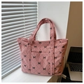 Detalle de la textura de bolso de pana rosa con lazos negros y costuras de rombos acolchados - Rosa