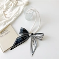 Détail du collier de perles avec ruban rayé noir et blanc sur un plateau blanc - Imprimé Lettres Noir Blanc