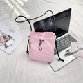 Pink nylon crossbody bag with drawstrings on white bedding with tech accessories - Pink