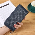 Deep blue woven leather long wallet held over a wooden table with lifestyle props - Dark Blue