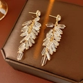 Detailed view of gold firecracker earrings with crystals and transparent tassels - 925 Sterling Silver Pin Tassel Style / Gold-Transparent