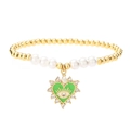 Beaded heart evil eye bracelet with gold beads and white pearls on white background - Green