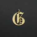 Detailed view of a gold gothic letter G pendant with a hanging ring on black surface - Letter G