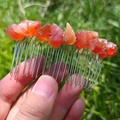 Peine de metal hecho a mano con cristales naranjas naturales sobre fondo de césped - Peine de Plata Ágata Roja Hilo de Plata