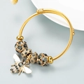 Detail view of golden spiral bracelet with rhinestone beads and a bee charm - Black