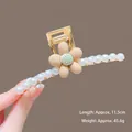 Detail view of a 11.5cm golden metal hair claw with pearls and a flower motif - K17 Coffee Large Flower