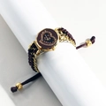 Detail of a gold watch with brown woven strap and crystal heart dial on a white display - Gold Case Coffee Dial