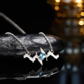 Macro shot of S925 silver heartbeat necklace with blue topaz stone on black stone base - Silver Natural Topaz Necklace