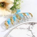 Detail showing the light blue and gold painted texture on a clear large hair claw clip - Blue