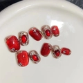 Close-up of handmade red and gold press-on nails with ruby stones and diamond accents - Medium (M) / Wine Red/Ultra-Short Coffin