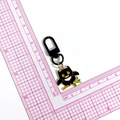 Cartoon black owl keychain with orange eyes and gold outline shown on scale - Owl (Black Clasp)