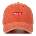 Detail of Hustle embroidery patch on washed cotton baseball cap with distressed texture - One Size / Orange